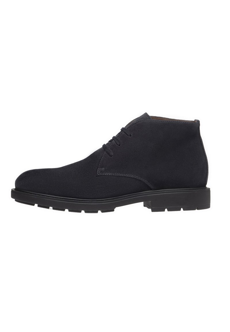 Stivaletti neri in suede con punta arrotondata e design con lacci; suola in gomma piatta, cuciture minime e silhouette semplice.