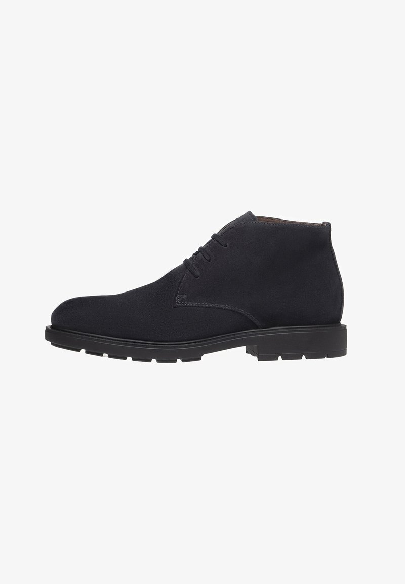 Stivaletti neri in suede con punta arrotondata e design con lacci; suola in gomma piatta, cuciture minime e silhouette semplice.