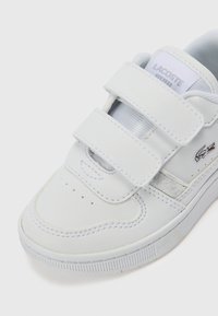 Sneakers en cuir blanc avec des bandes Velcro, embout perforé pour la ventilation et semelle en caoutchouc texturé. Comprend un petit logo brodé.