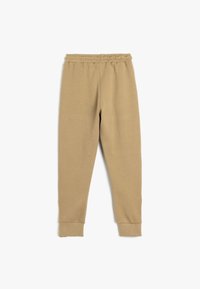 Beige sweatpants i bomuldsblanding med elastisk talje, tætsiddende manchetter og en glat tekstur. Enkel design uden mønstre eller yderligere detaljer.