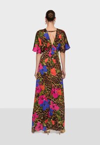 Robe longue avec un motif léopard en fond, ornée de grandes fleurs colorées en rose, bleu et vert. Dos en V et manches fluides.