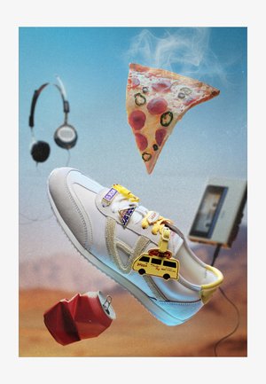 Sneaker bianco con spillette a tema pizza che galleggiano tra una fetta di pizza fumante, una lattina di soda schiacciata, cuffie e un lettore cassette.