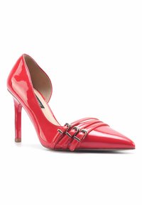 Red patent leather high-heeled shoe with a pointed toe, featuring three horizontal straps with metallic buckles across the front.