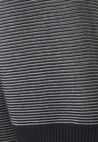 Suéter de punto con un patrón de rayas en azul oscuro y gris claro. Bajo y puños acanalados, textura suave, peso medio. Sin adornos visibles.