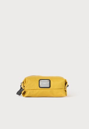 Trousse rectangulaire jaune zippée avec languette latérale en cuir noir et panneau d'étiquette transparent rectangulaire à l'avant.