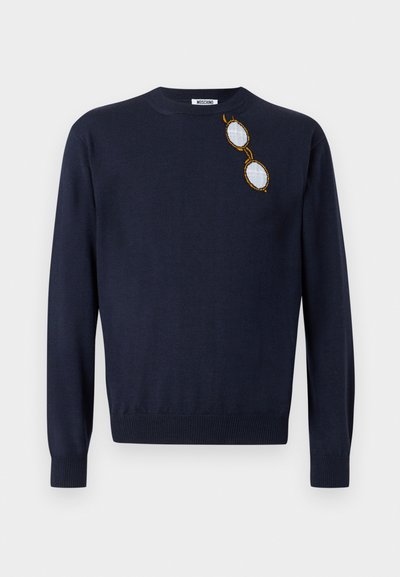 Pull bleu marine à col rond avec manches longues, présentant un petit motif brodé de lunettes rondes à monture dorée près de l'épaule gauche.