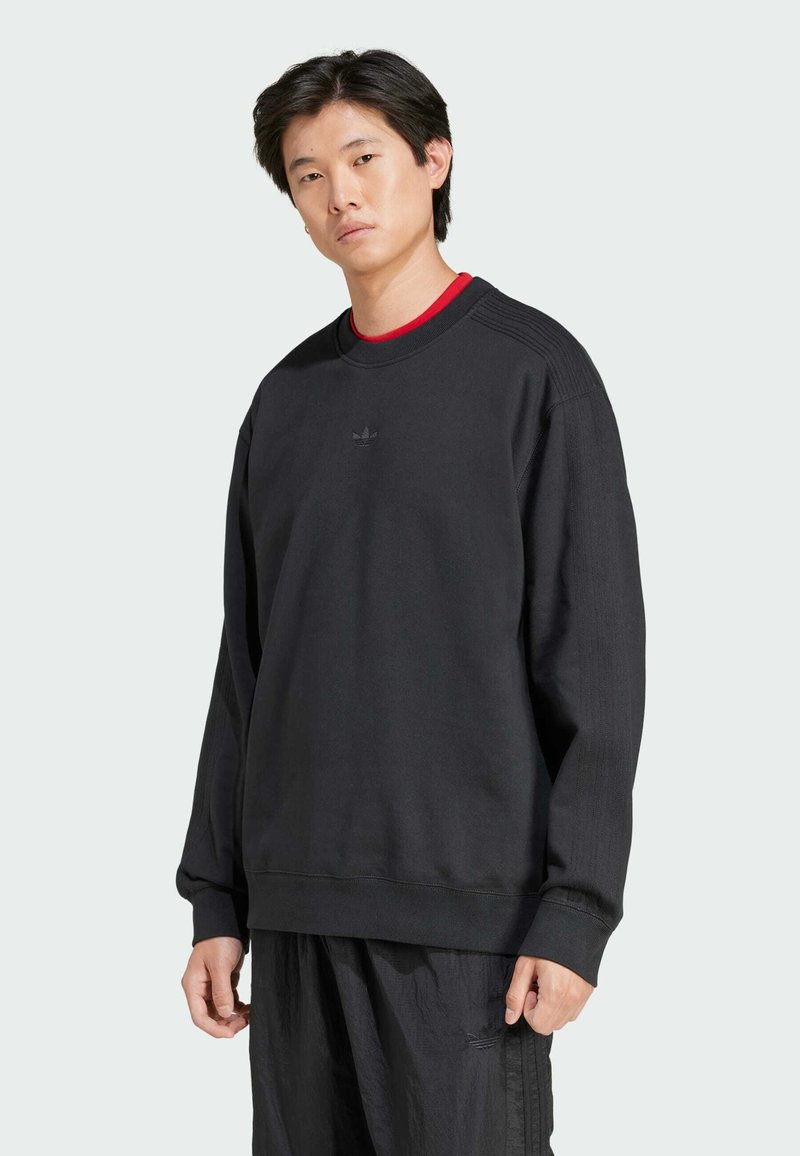 Sort sweatshirt i bomuldsblanding, rund hals, ribbede manchetter, diskret logo på brystet, parret med løse sorte bukser. Blød tekstur, afslappet pasform.