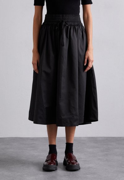 Gonna nera al ginocchio con vita arricciata e cordoncino. Realizzata in materiale leggero con una superficie liscia e un leggero lucido.