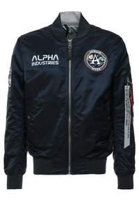 Chaqueta bomber de nailon azul marino con cremallera frontal, puños acanalados y parches de la NASA. Presenta un logo bordado y una etiqueta en la manga.