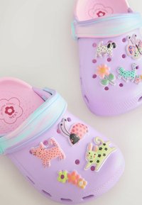 Zoccoli di plastica viola con vari adesivi colorati di animali e fiori, con interno rosa e cinturino a contrasto.