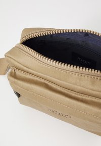 Borsa in tessuto khaki con chiusura con zip, tasca interna con zip, dettaglio logo. Texture liscia, forma rettangolare compatta.