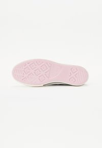 Sneaker-sula med en texturerad rosa gummibotten och vita sidor. Har geometriska mönster för grepp och design detaljer.