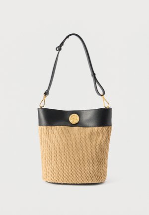 Πλεκτή μπεζ τσάντα τύπου κάδο με μαύρο δέρμα στο φινίρισμα, ρυθμιζόμενο λουράκι ώμου και χρυσό κυκλικό κούμπωμα σε μονόχρωμο φόντο.