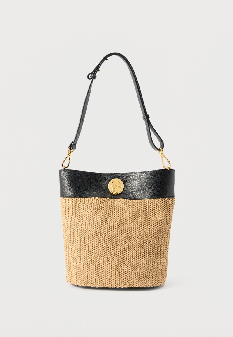 Πλεκτή μπεζ τσάντα τύπου κάδο με μαύρο δέρμα στο φινίρισμα, ρυθμιζόμενο λουράκι ώμου και χρυσό κυκλικό κούμπωμα σε μονόχρωμο φόντο.