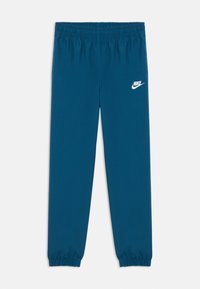 Plave Nike trenirke s elastičnom trakom u struku i na manžetama, s bijelim Nike logotipom na gornjem lijevom bedru.
