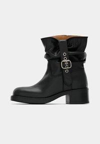 Must have mustan nahast pahkluu saapad, millel on kortsus varre osa, külgneb vöö tõttu ja plokk-konts. Sile tekstuur ja ümmargune varvas.