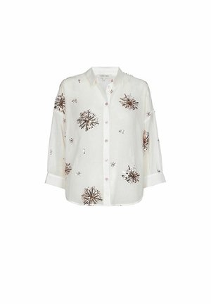 Weißes Hemd mit langen Ärmeln und Knopfleiste, verziert mit braunen und schwarzen Pailletten in Form von Sternexplosionen, die über den Stoff verteilt sind.