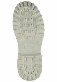 White rubber shoe sole with deep tread patterns, featuring cross-shaped indentations and rounded edges. Brand logo embossed on the heel area.