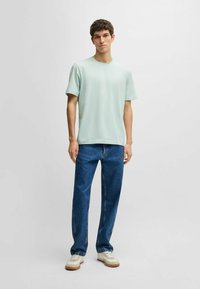 Light green short-sleeve t-shirt, accompanied by blue straight-leg jeans and beige sneakers. Simple design, soft texture, and casual fit.