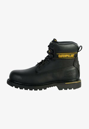 Stivale da lavoro in pelle nera con accenti gialli, punta in acciaio, design con lacci, finitura texturizzata e suola in gomma robusta con scanalature profonde.