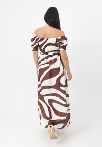 Robe longue décolletée, ornée d'un motif abstrait marron et blanc, avec un corsage froncé et des manches bouffantes, fabriquée dans un tissu lisse.