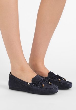 Suedes mokkaer i navy blå har en rund tå, snøre detaljer, guldtone hardware accenter og en fleksibel sål.