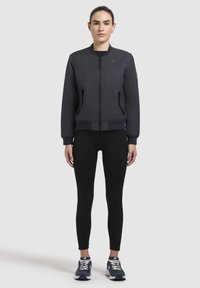 Tumesinise bomber-jakk ribatud mansettide ja äärega, ees lukuga, küljetaskute ja logosilmaga. Kantud mustade retuuside ja jooksujalatsitega.