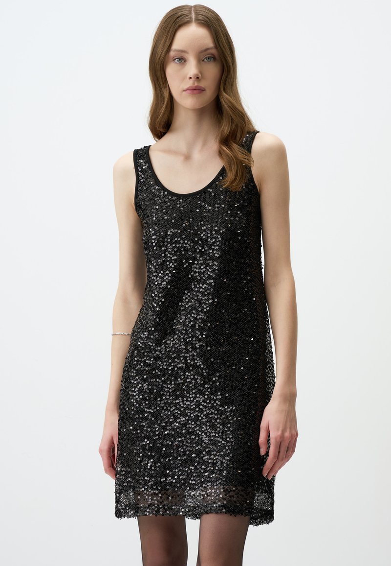 Robe sans manches noire ornée de paillettes avec un col en forme de cœur, affichant une coupe ample et une texture lisse, atteignant la longueur mi-cuisse.