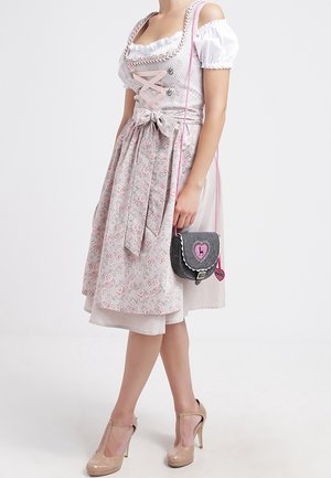 Traditionelles Dirndl mit einem Rock in Blumenmuster, weißen Puffärmeln und einem rosa Schnürmieder; kombiniert mit einer kleinen Tasche mit Herzakzenten.