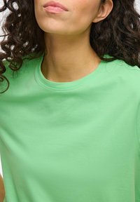 Kortærmet t-shirt i livlig grøn bomuldsstof, med rund halsudskæring og glat tekstur uden synlige mønstre eller accenter.