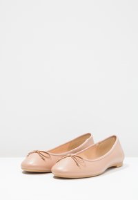 Rosafarbene Ballerinas aus Leder mit runder Zehenpartie, minimalistischer Schleifendetail und flachem Absatz. Glatte Textur und schlichtes Design.