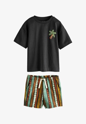 Schwarzes kurzärmliges Hemd mit kleinem grünem Palmenmuster, kombiniert mit Shorts mit Kordelzug und vertikalen, mehrfarbigen geometrischen Streifen.