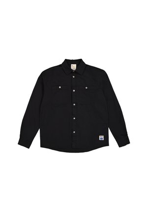 Camisa negra de manga larga con botones, dos bolsillos en el pecho, broches plateados y dobladillo curvado. Presenta una etiqueta en la parte inferior izquierda.