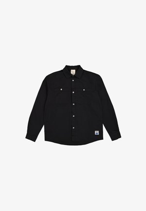 Schwarzes langärmliges Hemd mit Knopfleiste, zwei Brusttaschen, silbernen Druckknöpfen und abgerundetem Saum. Enthält ein Etikett an der unteren linken Seite.