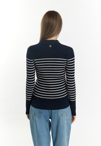 Marineblau gestreifte Langarmbluse mit gerippter Textur, ausgestattet mit weißen horizontalen Streifen und einem Kragen. Der Rücken enthält ein kleines Logodetail.