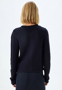 Marinblått stickat tröja med texturerat mönster, rund halsringning och långa ärmar. Ribbad nederkant och ärmslut. Designad för en avslappnad passform.