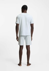 Vaaleanharmaa lyhythihainen t-paita ja siihen sopivat shortsit, valmistettu pehmeästä materiaalista, sileä pinta, rento istuvuus, eikä näkyviä kuvioita tai koristeita.