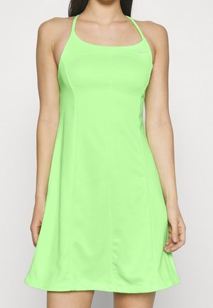 Femme portant une robe Nike sans manches vert néon avec des bretelles fines, un corsage ajusté et une jupe évasée sur fond blanc uni.