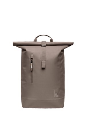 Plecak roll-top w kolorze taupe z przednią pionową kieszenią na suwak, zapięciem na pasek z klamrą oraz logo „GOT BAG.” w dolnym prawym rogu.