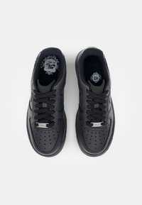 Svarta Nike Air Force 1-sneakers med en slät läderöverkropp, perforeringar på tån och svarta snören. Har silverdetaljer på tungan.