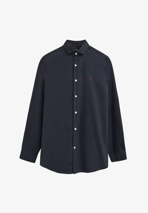 Marineblaue, langärmlige Hemd mit weißen Knöpfen und einer kleinen roten Stickfigur auf der linken Brustseite.