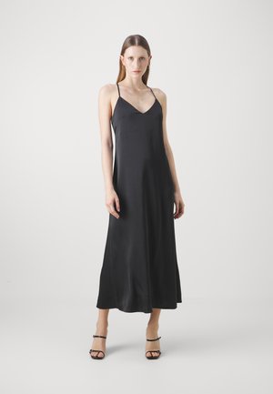 Black satin slip dress with a V-neck, thin straps, and a full-length silhouette. Smooth texture and minimalist design. Black strappy heels.