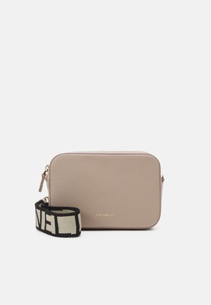 Sac bandoulière rectangulaire beige en cuir avec surface texturée, fermeture éclair dorée et large sangle réglable noir et blanc avec texte en gras.