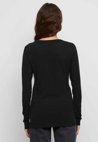 Zwarte lange mouwen shirt van zachte katoen, met een ronde halslijn en een rechte snit, met zijsplits voor extra bewegingsvrijheid.