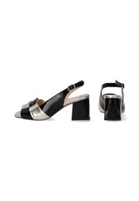 Zwarte patent slingback schoenen met een metallic gouden accent en een vierkante hak. Voorzien van een ronde neus en een gespsluiting op de enkelband.