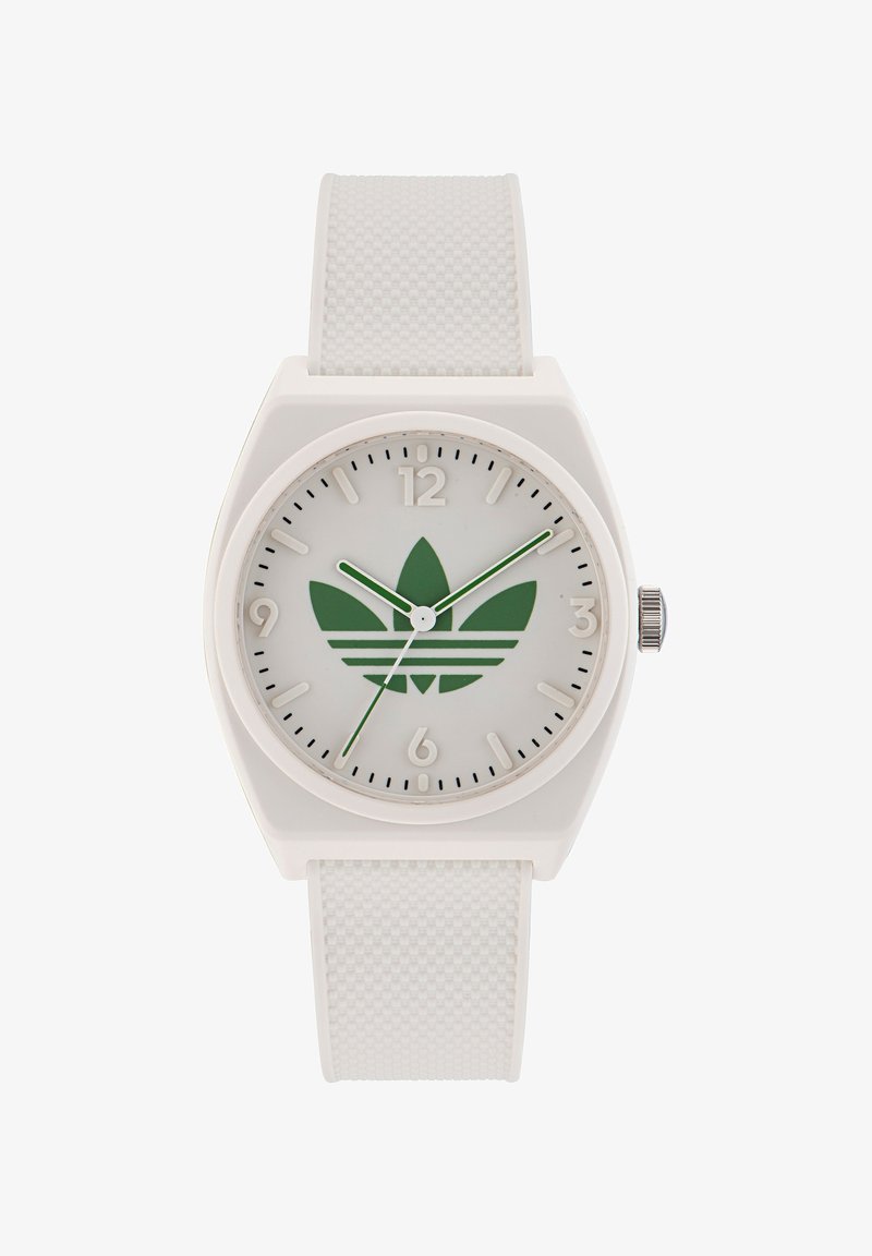 Bela plastična ura z teksturiranim belim trakom, okroglo stikalo, zelenim logotipom s tremi črtami in črnimi kazalci za ure. Srebrna krona na strani.