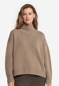 Beige Rollkragenpullover mit grober Rippstruktur, lockerer Passform, überschnittenen Schultern und breiten Bündchen. Verfügt über einen hohen Kragen und einem geraden Saum.