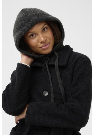 Mustat fleece-takit, joissa on harmaa huppu, napitus, kiristysnauha ja teksturoitu kangas. Rennon tyylin isoilla taskuilla.