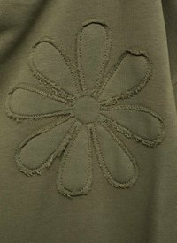 Olijf groene stof met een gestikt bloemenpatroon met zes bladeren en een centrale cirkel, die een gestructureerde, verhoogde rand toont.