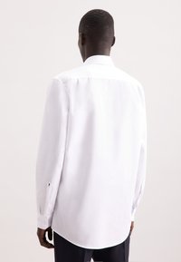 Witte lange mouwen overhemd met een standaard kraag, knoopmanchetten, een gebogen zoom en een soepele textuur, met een minimalistisch ontwerp.